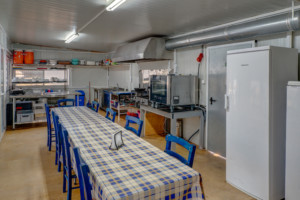 Küche mit Kühlschrank und großem Esstisch im griechischen Freizeithaus Strandlodges Panorama für Gruppenreisen.