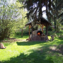 Feuerstelle mit Lehmbackofen im Garten am Freizeithaus Gästehaus Harz für barrierefreie Gruppenreisen in Deutschland.