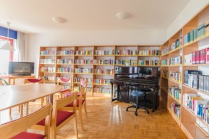 Gruppenraum mit Bibliothek, TV und Klavier im Gruppenhotel Zittauer Gebirge in Deutschland.