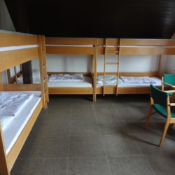 Ein Schlafzimmer mit Etagenbetten und Sitzgruppe im Gruppenheim Freizeitheim Settrup für Kinder und Jugendfreizeiten in Deutschland.