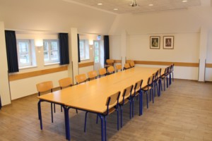 Ein Gruppenraum mit großem Tisch und vielen Stühlen im dänischen Freizeitheim Tydal.
