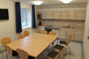 Ein Gruppenraum mit Küchenzeile, TV und Esstisch im dänischen Freizeithaus Tydal für Kinder und Jugendgruppen.