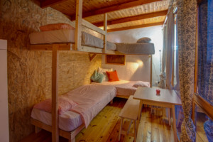 Ein Schlafzimmer mit Hochbetten und Sitzgruppe im Gruppenhaus Strandlodges Panorama in Griechenland.