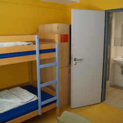 DEHE Ein Schlafzimmer mit eigenem Bad im Freizeithaus Heliand für Kinder und Jugendfreizeiten in Deutschland.