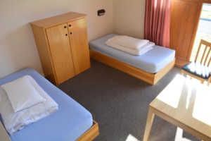 Ein Schlafzimmer mit Betten, Tisch und Kleiderschrank im irischen Freizeithaus Donegal Hostel.
