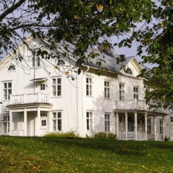 Das schwedische Freizeithaus Berga Gård liegt auf einem grünen Hügel.