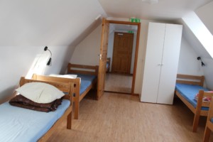 Holzbetten und Kleiderschrank in einem Mehrbettzimmer im schwedischen Gruppenhaus Tygegården für Kinder und Jugendreisen.