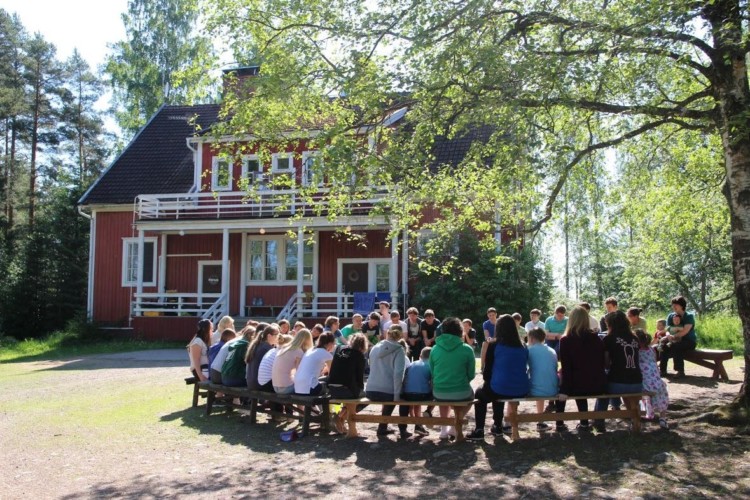 Sitzkreis unter Bäumen am finnischen Freizeithaus Vanamola für Kinder und Jugendgruppen.