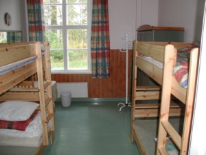 Ein Mehrbettzimmer mit Holzbetten im Gruppenheim Vanamola in Finnland am See.